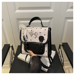 Détails du sac collège rose avec motif de nœuds, pendentif perle et dentelle