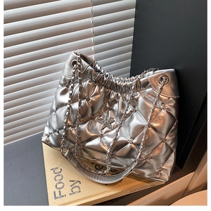 Detail of silver quilted chain bag with star metal accent and textured surface