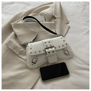 Macro detail of white patent leather shoulder bag with silver studs and metal buckle strap