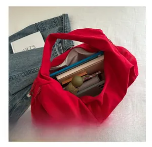 Internal storage detail of red nylon tote bag with umbrella, tablet, and daily essentials