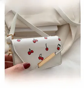 Close-up of white leather mini bag with cherry print and golden hardware detail
