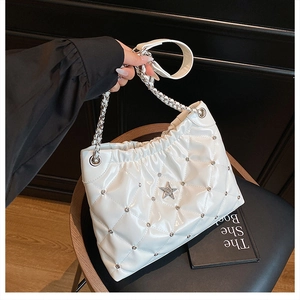 Close-up of white quilted leather bucket bag with silver star and chain strap