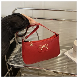 Close-up of red leather handbag with gold bow hardware and flower zipper charm