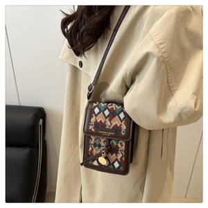 Close-up of a small vintage crossbody bag with geometric woven patterns and gold charm