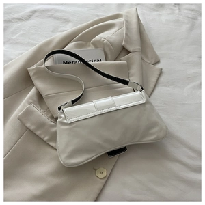 Close-up of white glossy patent leather underarm bag with black and white strap