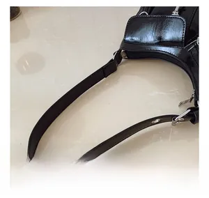 Detail of glossy black patent leather handbag with silver metallic hardware and rivets