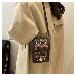 Close-up of small crossbody bag featuring retro geometric weave and leather trim on a model