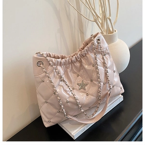 Close-up of pink quilted bucket bag with silver studs and a large metallic star ornament