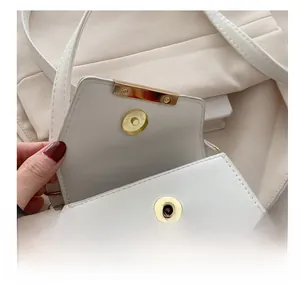 Detail of the high-quality magnetic metal buckle on a white leather shoulder bag
