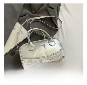 Detail of silver handbag with gold bow, white lace trim and heart embroidery accents