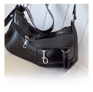 Detailed view of the black glossy crescent bag with silver zippers and pocket features