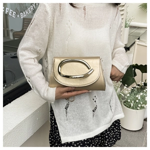 Pochette de soirée dorée champagne avec boucle en métal ovale dans un décor de café