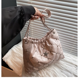 Close-up of pink quilted bucket bag with silver studs, star logo, and chain strap detail