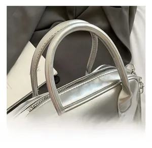 Detail of silver handbag with metallic bow accent and smooth zipper closure