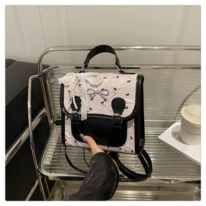 Détail du mini sac à dos rose gaufré avec nœuds noirs et breloque en dentelle