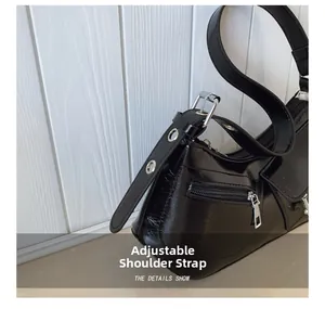 Detail of adjustable pin buckle strap on black shiny Y2K crescent bag with silver hardware