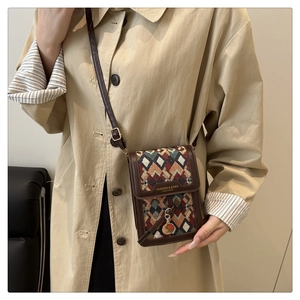Detail of vintage crossbody bag showing geometric pattern and leather strap with coat