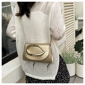 Détail du sac bandoulière doré métallisé avec grande boucle anneau et chaîne fine dorée