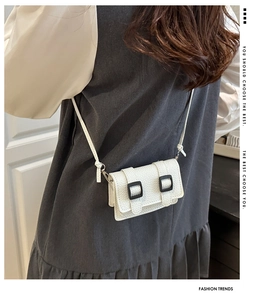 Dettaglio mini borsa a tracolla bianca con motivo litchi e doppie fibbie nere decorative