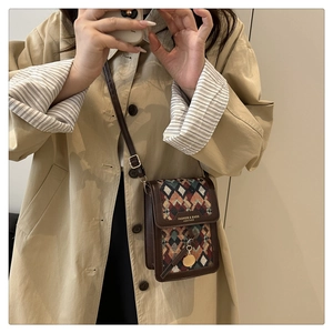 Detail of vintage crossbody bag with geometric patterns and brown leather trim