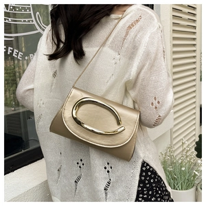 Detail of champagne gold evening bag showing a large oval metal buckle and glossy texture