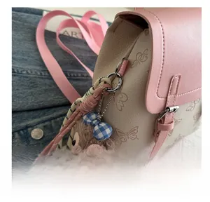 Detail of pink mini backpack with butterfly texture and cute plush bear charm accessory