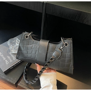 Close-up of black crocodile embossed bag with twisted woven handle and silver metal rings