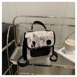 Détail du sac à dos rose et noir avec imprimé nœuds et breloque en perles sur étagère