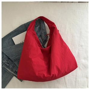 Detail of red oversized nylon hobo bag styled with a denim jacket and art book