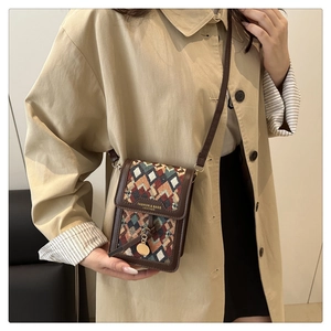 Detail of a mini crossbody bag with colorful woven patterns and brown leather trim on a model