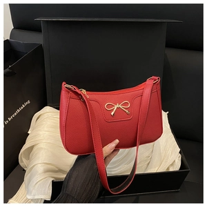 Detail of red pebbled leather underarm bag with gold bow buckle in a luxury gift box