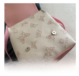 Detail showing dual magnetic closures and pink butterfly pattern on white leather bag