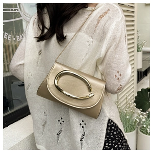 Detail of champagne gold chain bag with a large metallic ring buckle on white knitwear