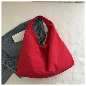Flat lay of red nylon tote bag with drawstring detail on blue denim background