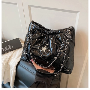 Detail of black quilted leather bucket bag with star crystal decor and silver chain strap