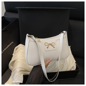 Detail of white litchi pattern bag with golden bow decoration inside a gift box