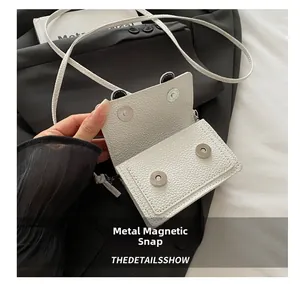 Dettaglio della mini borsa in pelle litchi bianca con doppia chiusura magnetica sicura