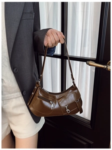 Close-up of a dark brown crescent shoulder bag with silver zippers and front pocket