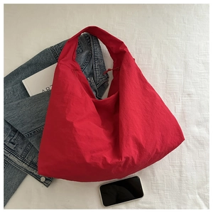 Large red hobo tote bag in textured nylon fabric styled with casual denim and books