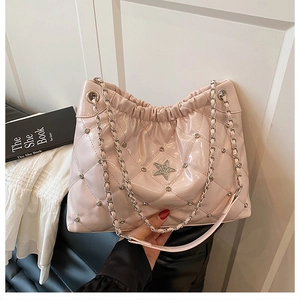 Detail of light pink quilted bucket bag with sparkly star logo and silver chain strap