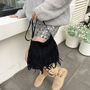 Fashionable black faux suede shoulder bag with long fringes in a street style look