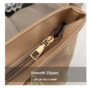 Close-up of a smooth gold metal zipper on a beige textured large-capacity tote bag