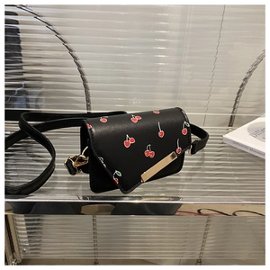 Detail of black leather crossbody bag with cherry prints and a golden metal buckle