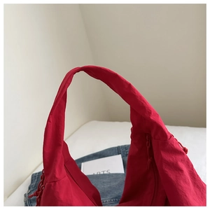 Detailed close-up of vibrant red hobo bag showing nylon texture and zip detailing