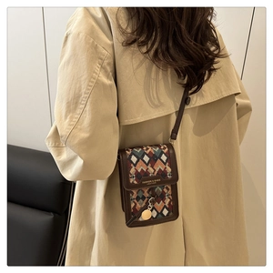 Detail of crossbody phone bag featuring geometric jacquard fabric and brown leather trim