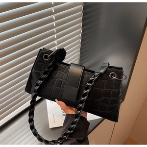 Detailed view of black crocodile pattern baguette bag with woven strap and metallic ring