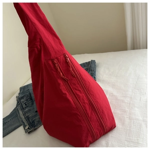 Detail of red geometric triangular tote bag with dual zippers and textured nylon fabric