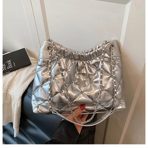 Detail of silver quilted bucket bag featuring a sparkling star charm and chain strap