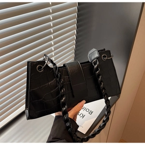 Close-up of black crocodile pattern leather bag with thick woven shoulder strap detail
