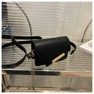 Detail of black minimalist square bag with gold metal buckle and leather shoulder strap